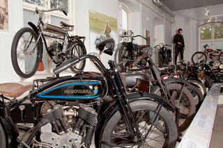 Eine Museumsausstellung mit Husqvarna-Oldtimer-Motorrädern und einer Nahaufnahme eines klassischen Modells.