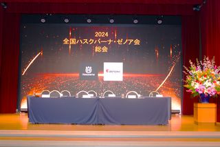 2024 年のハスクバーナ カンファレンスのステージセットアップには、テーブル、椅子、フラワーアレンジメントが設置されています。