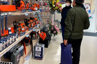 チェーンソーや園芸工具の陳列を眺める店内の2人。