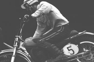 Eine Person, die ein Motorrad mit der Nummer 5 auf einem Feldweg fährt.