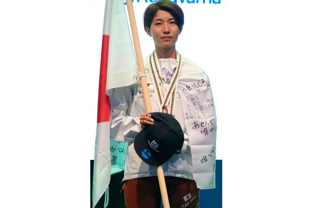 イベントで旗を持ち、メダルをかぶり、帽子を手にしている人。