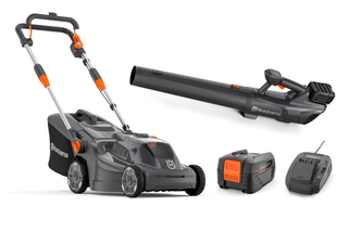 Front view of a Husqvarna lawn mower, leaf blower, battery, and charger set.