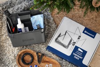 Temporärer Husqvarna Zaunset mit Zubehör auf einer Holzoberfläche angezeigt.