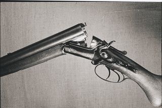 Vista lateral de una antigua escopeta de doble cañón con intrincados grabados.