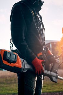Une personne tenant un produit dans un champ au coucher du soleil, portant des vêtements de travail.