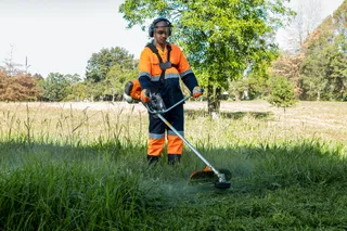 A person using a grass trimmer in a grassy field.