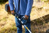A person using a grass trimmer in a garden setting.