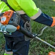 A person using a grass trimmer in a garden setting.