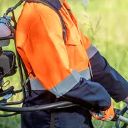 A person operating a brush cutter in a grassy area.