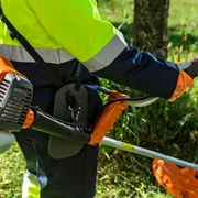 A person using a grass trimmer in a garden setting.
