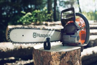 En motorsåg från Husqvarna som vilar på en stubbe i en skogsmiljö.