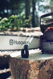 En motorsåg från Husqvarna som vilar på en stubbe i en skogsmiljö.