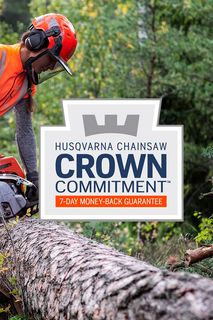 A person using a chainsaw to cut a fallen tree trunk in a forest setting.