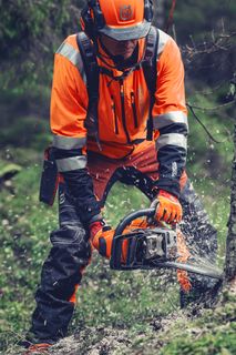 Een persoon die een kettingzaag gebruikt om een boom om te hakken in een bosomgeving.