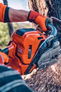 Una persona che utilizza una motosega Husqvarna per tagliare un tronco d'albero all'aperto.