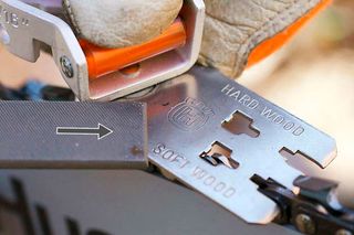 Close-up of a chainsaw blade with markings for hard and soft wood.