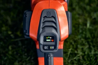 Close-up van het bedieningspaneel van een Husqvarna-product met een digitaal display, op een met gras begroeide ondergrond.
