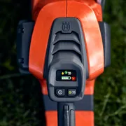 Close-up van het bedieningspaneel van een Husqvarna-product met een digitaal display, op een met gras begroeide ondergrond.