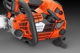 Zijaanzicht van een Husqvarna-kettingzaag met zichtbare bedieningselementen en handgreep.