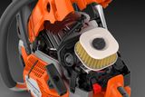 Страничен изглед на верижен трион Husqvarna с открит двигателен отсек, показващ въздушния филтър.