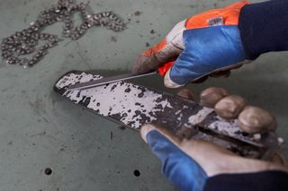 Una persona afilando la hoja de una motosierra con una lima en un banco de trabajo.