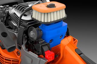 Close-up view of a chainsaw engine with visible air filter and spark plug.