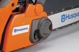 Közeli kép egy Husqvarna láncfűrészről, amely a láncot és a motorház egy részét mutatja.