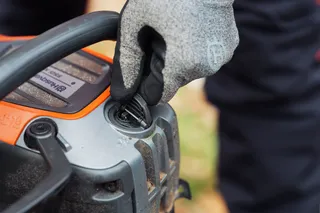 En person som justerar tanklocket på en motorsåg från Husqvarna.