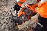 En person som använder en motorsåg från Husqvarna för att kapa en stor trädstock.