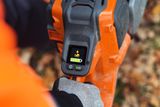 En person som håller i en Husqvarna-produkt som visar batterifacket och skärmen.