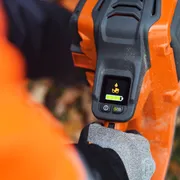 En person som håller i en Husqvarna-produkt som visar batterifacket och skärmen.