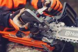 Osoba regulująca napięcie łańcucha w pilarce Husqvarna.