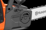Close-up of Husqvarna chainsaw side cover with bar, chain, tension dial and locking knob.