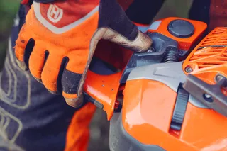 Osoba v pracovných rukaviciach, ktorá nastavuje komponent na produkte Husqvarna.