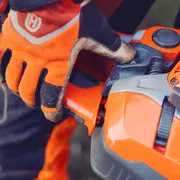 Osoba v pracovných rukaviciach, ktorá nastavuje komponent na produkte Husqvarna.