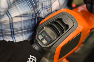 Een persoon die een Husqvarna-product vasthoudt en het gebruiksvriendelijke bedieningspaneel demonstreert.