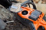 En person som underhåller en motorsåg från Husqvarna, med fokus på luftfiltret och batteriutrymmet.