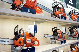 Display of Husqvarna chainsaws on shelves in a store setting.