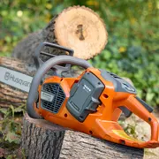 Husqvarna 435i. A Husqvarna chainsaw resting on a cut tree log in a garden setting.