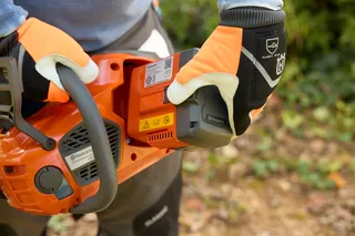 Husqvarna 435i. A person holding a Husqvarna product, showcasing the battery compartment.