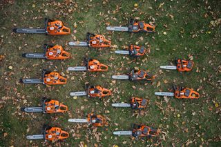 Toppvisning av flere Husqvarna-motorsager arrangert på gress med løv.