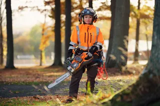 HUSQVARNA 550i XP®. A person in work gear holding a Husqvarna chainsaw in a forest setting.