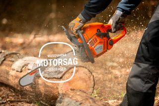 En person som kapper en stokk med en motorsag fra Husqvarna, sagflis som flyr i skogen.