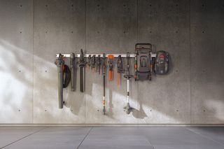 A set of gardening tools and equipment neatly organized on a wall rack.