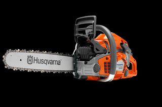 Side view of a Husqvarna chainsaw with visible chain and handle.