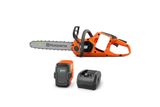 Side view of a Husqvarna battery-powered chainsaw with a battery and charger.