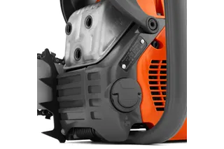 Close-up view of a chainsaw engine and oil cap, showcasing mechanical details.
