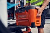 Особа, яка кладе коробку для зберігання C1000X4 Husqvarna в транспортний засіб.