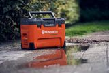 Футляр для інструментів Husqvarna C1000X4 на мокрому асфальті поруч із калюжею.