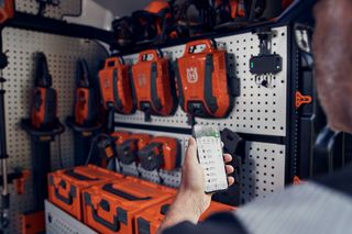 Una persona che utilizza un'app per smartphone per gestire i prodotti Husqvarna stoccati in un furgone.